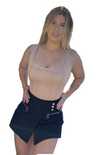 Load image into Gallery viewer, Woman wearing a beige top and black skirt with gold buttons outdoors.
